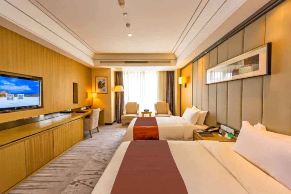 Ein Hotelzimmer mit einem Bett, einem Schreibtisch, einem Fernseher und einer Sitzecke mit Stühlen.