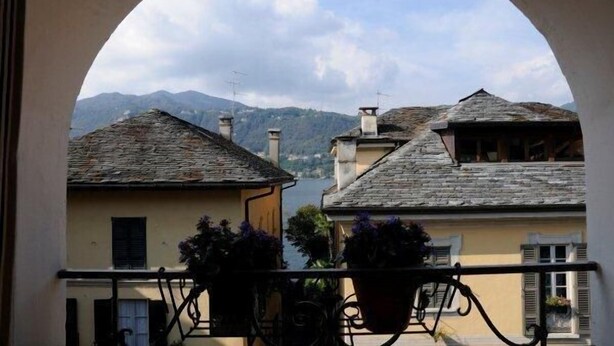 Un balcon donnant sur des bâtiments en pierre et offrant une vue sur la montagne.