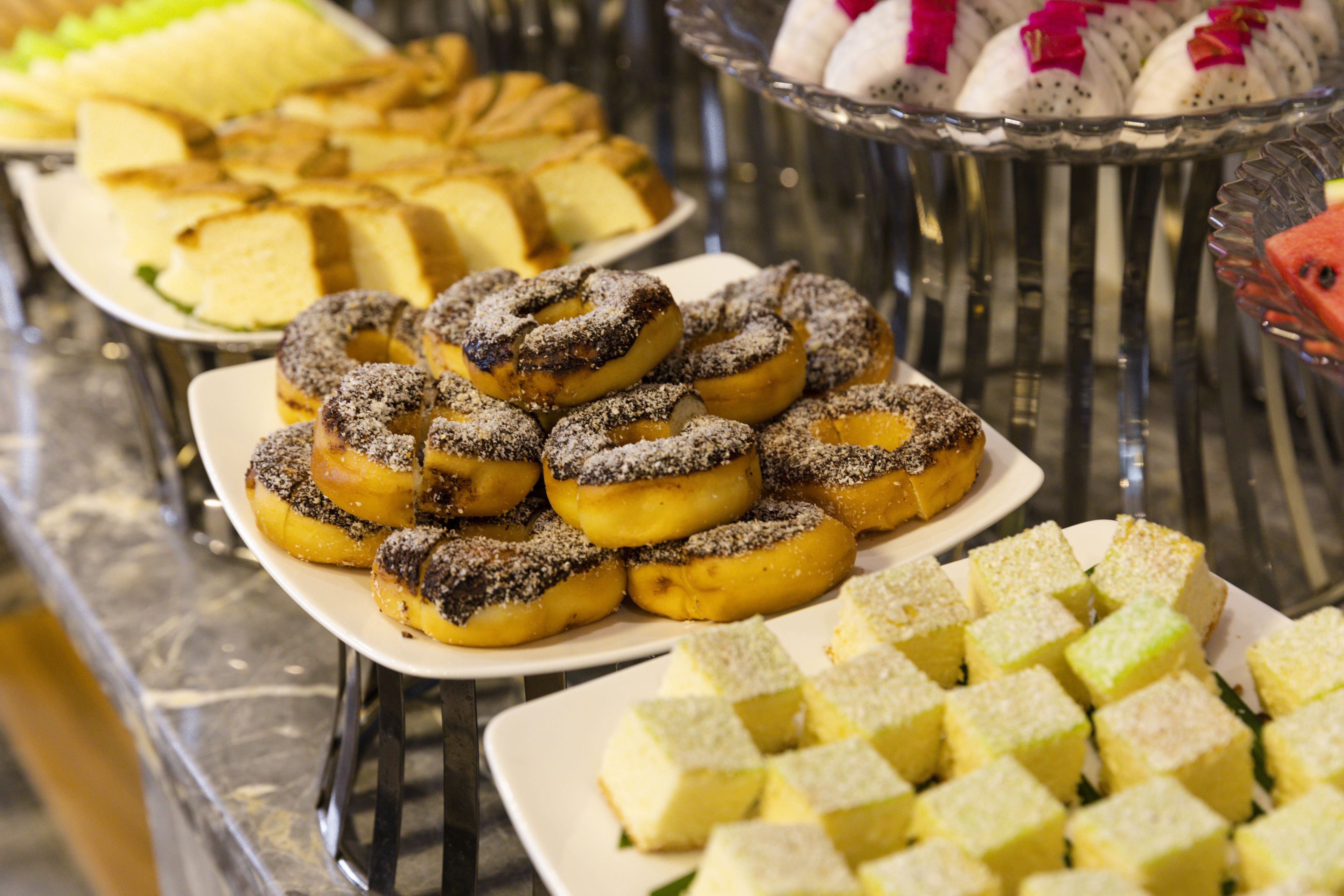 Un bufé con diversos postres, incluyendo rosquillas y cuadrados de pastel.