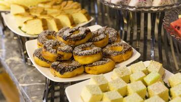 Un bufé con diversos postres, incluyendo rosquillas y cuadrados de pastel.