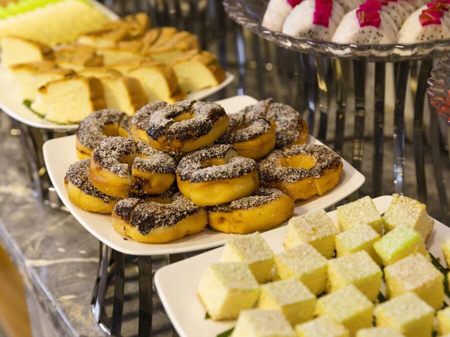 Un bufé con diversos postres, incluyendo rosquillas y cuadrados de pastel.