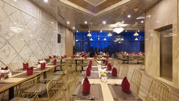 A spacious restaurant with marble walls, multiple dining tables, and golden chairs.