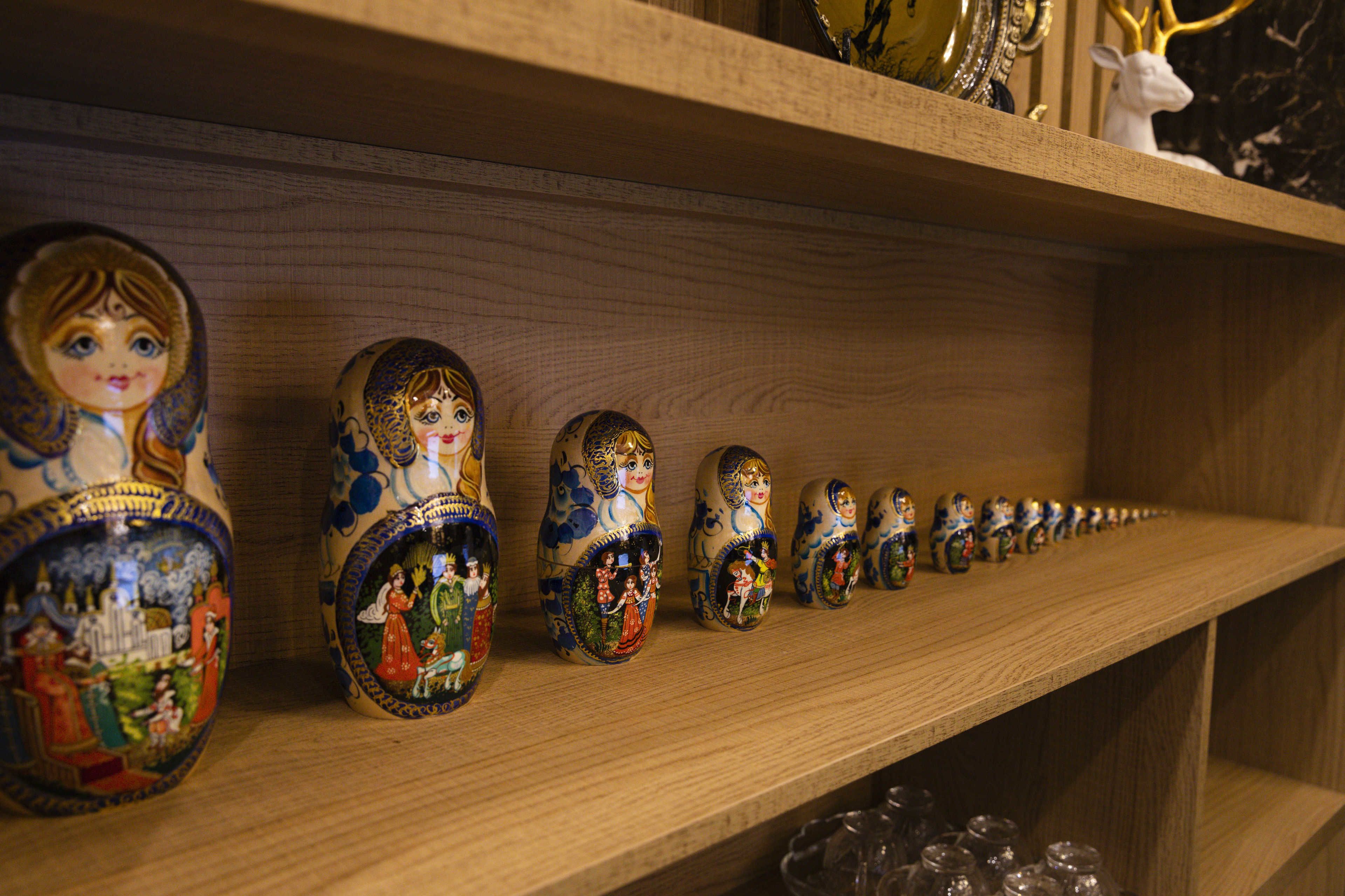 Une étagère en bois où sont exposées une rangée de poupées russes (matriochkas) peintes avec de fins détails.