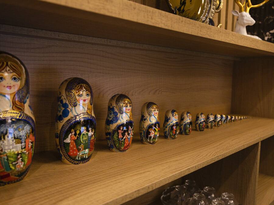 Une étagère en bois où sont exposées une rangée de poupées russes (matriochkas) peintes avec de fins détails.