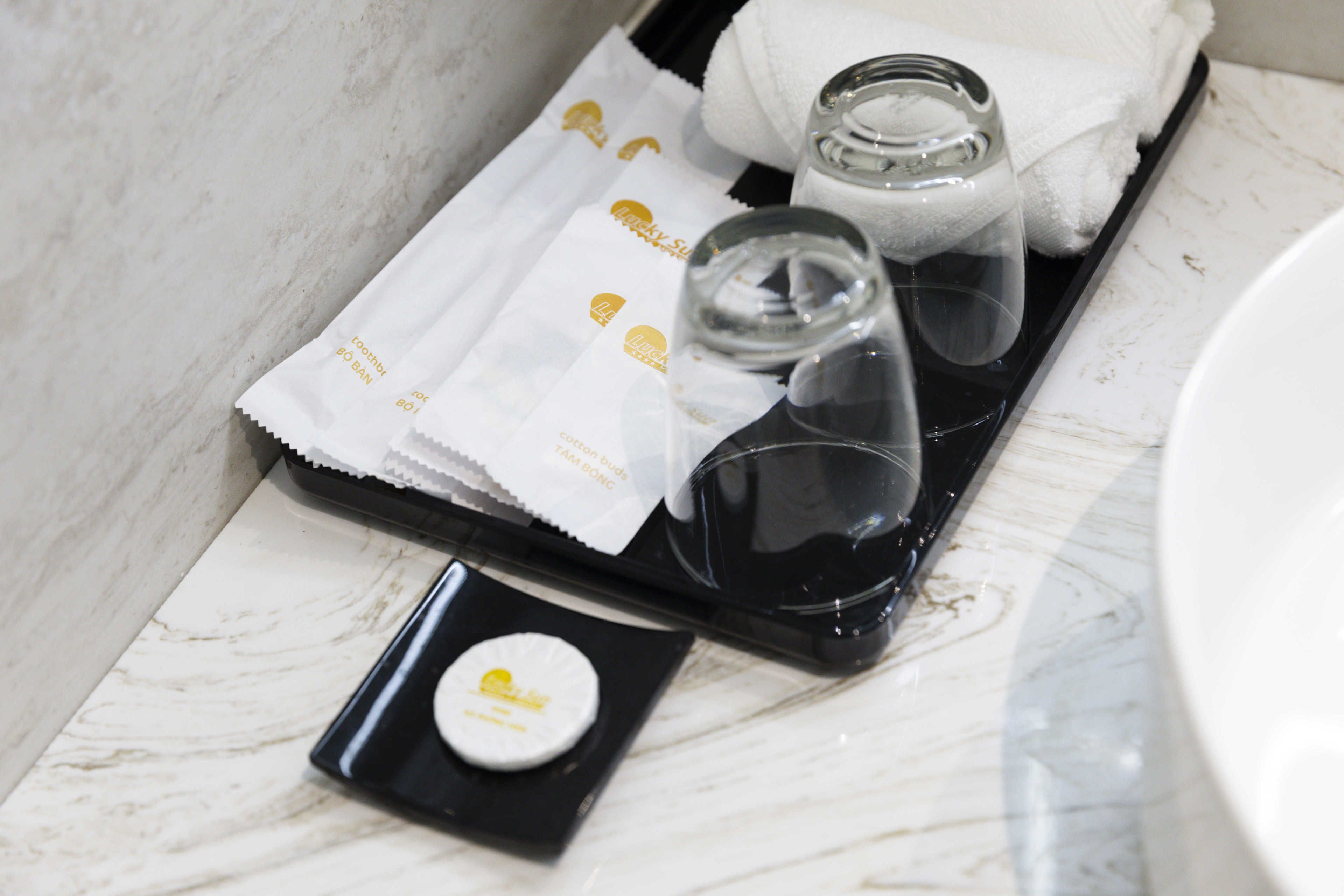 A tray with a glass, a small container, and a towel on a marble surface.
