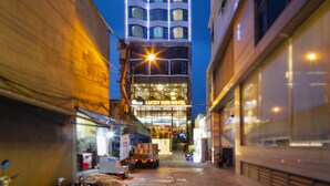 Un edificio de hotel alto con varios pisos y balcones, una entrada bien iluminada y un letrero visible del Hotel Lucky Sun.