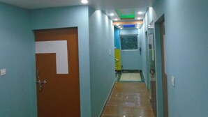 A hallway with a brown door, a blue wall, and a ceiling with recessed lighting. - Hotel Radiation (Deoghar)