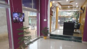 A hotel lobby with a reception desk, potted plants, and a television screen. - Hotel Radiation (Deoghar)