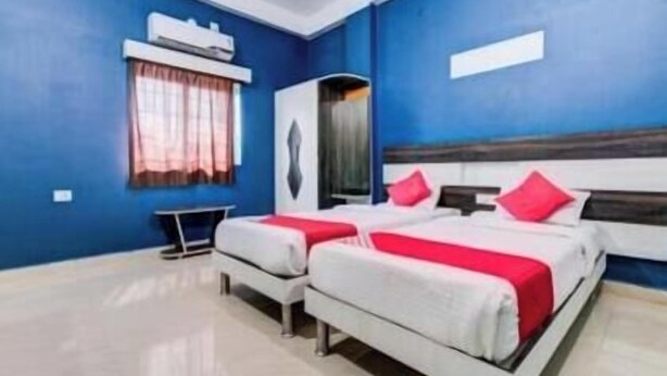 A hotel room with two beds, a desk, and a window with curtains. - Hotel Radiation (Deoghar)