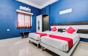 A hotel room with two beds, a desk, and a window with curtains. - Hotel Radiation (Deoghar)