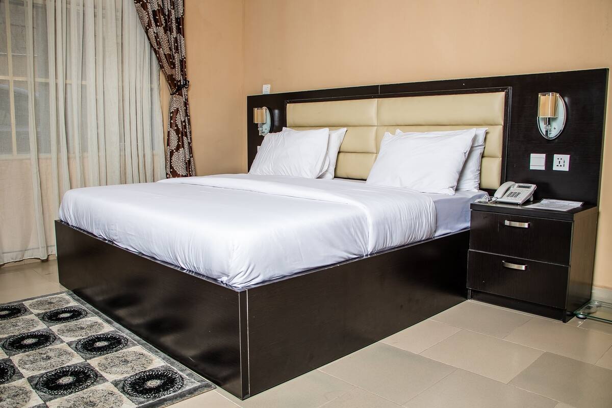 A modern hotel room with a large bed, a bedside table, and a nightstand.