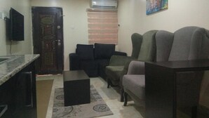 A living room with a sofa, a coffee table, and a TV mounted on the wall. - The Capital Apartments (Abuja)