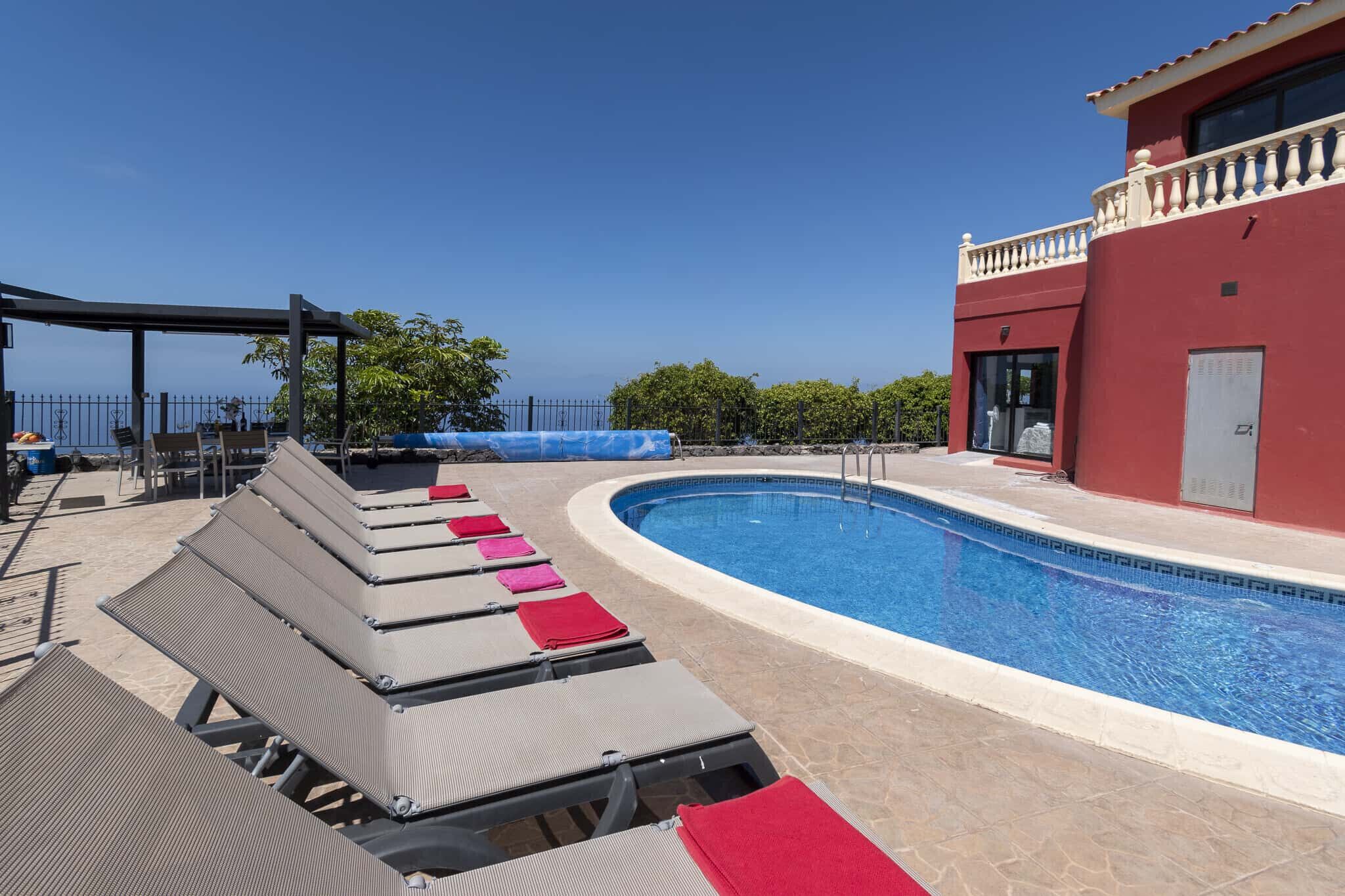 A pool area with lounge chairs and a building with a red facade.