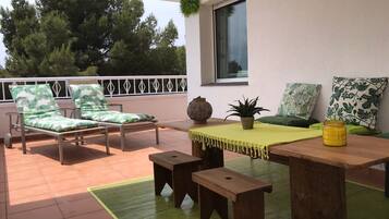 Relax on the terrace with lounge chairs, a wooden table, and a potted plant.