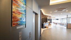A modern interior with a reception desk, a large abstract painting, and a spacious area with tables and chairs. - Washington R&B Hotel Nagoya Shinkansenguchi (Nagoya)