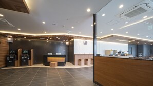 A modern reception area with a wooden reception desk, a digital kiosk, and a seating area. - Washington R&B Hotel Nagoya Shinkansenguchi (Nagoya)