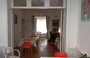 Un comedor con una mesa dispuesta para cuatro personas, rodeada de sillas, una araña y una chimenea.