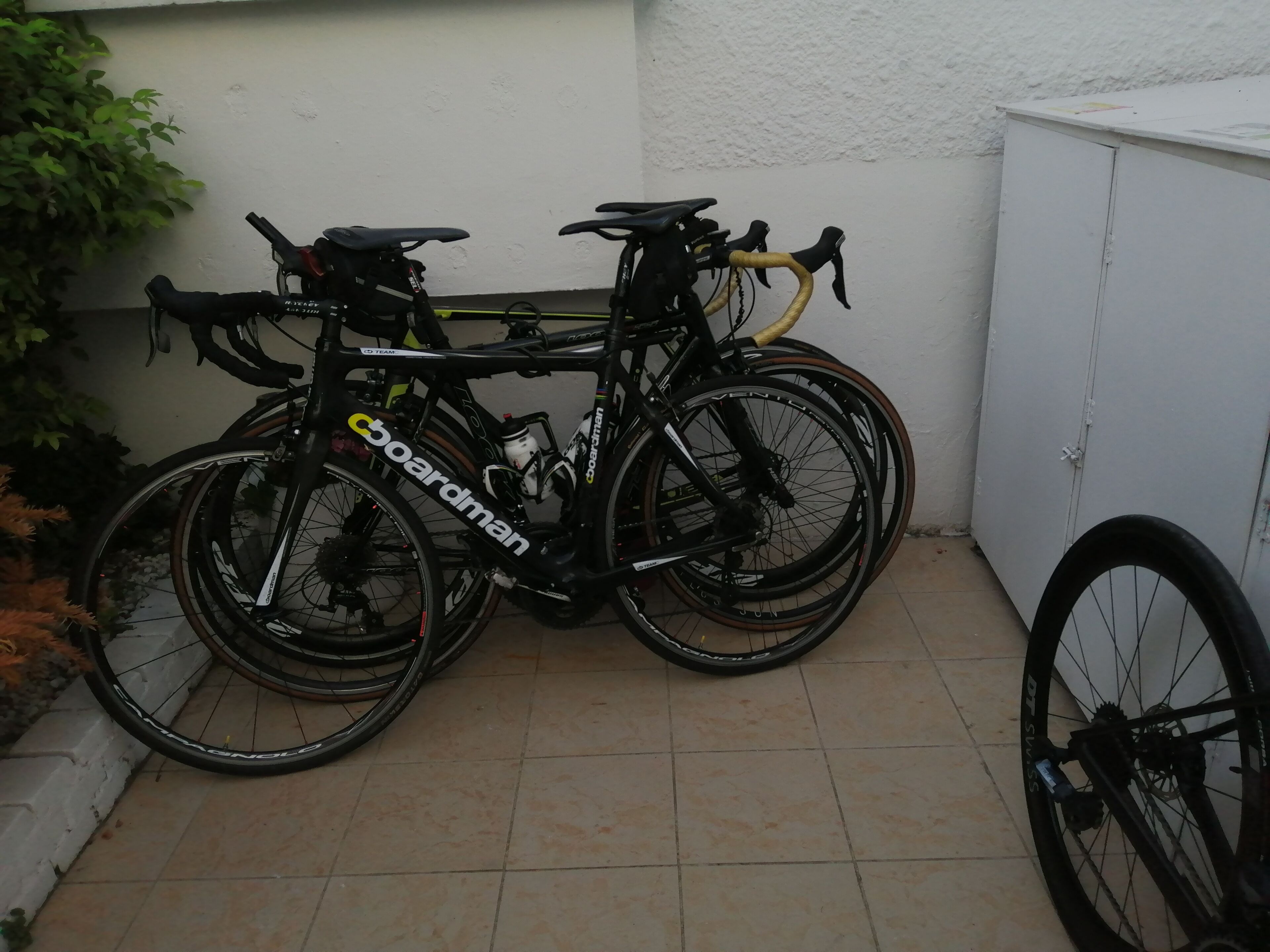 Two bicycles parked against a wall in a tiled area.
