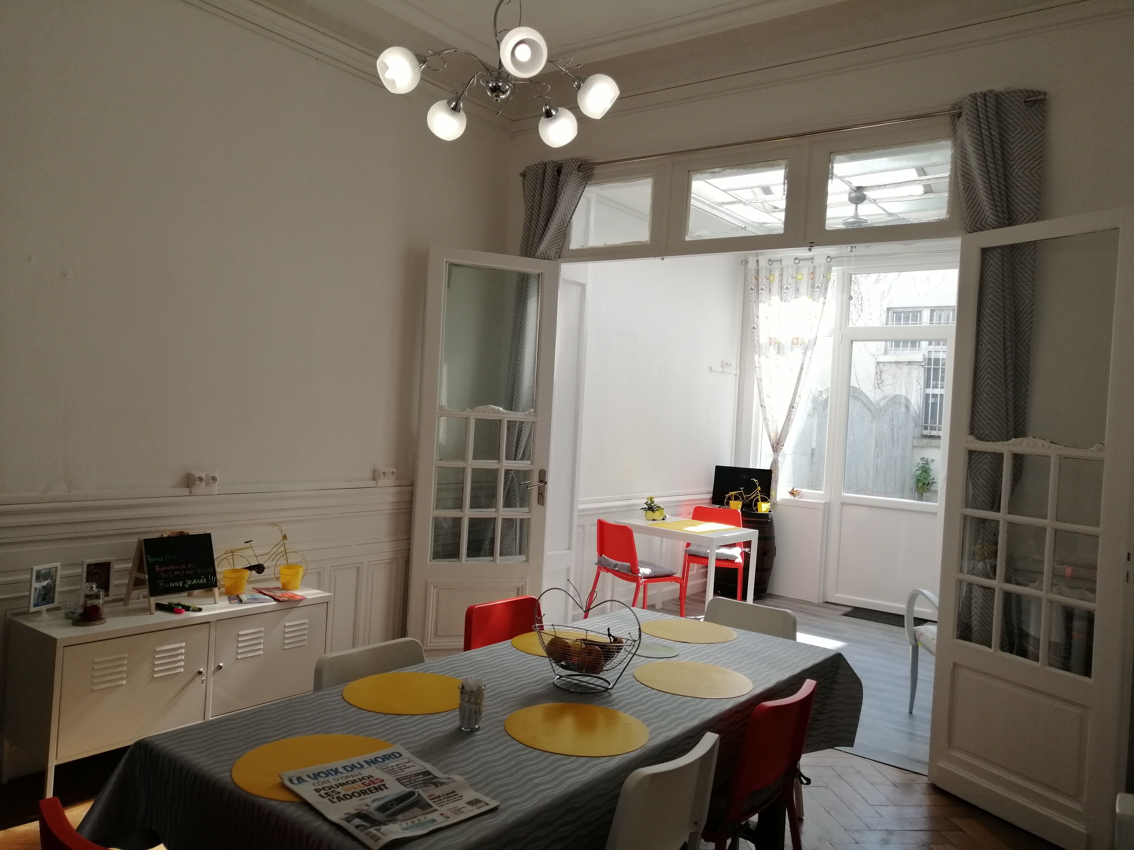 A dining area with a table set for four, a laptop on a small table, and a window with curtains.