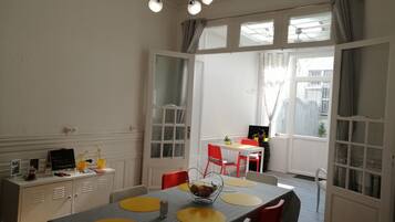 A dining area with a table set for four, a laptop on a small table, and a window with curtains.