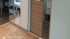 Un dormitorio con puerta de madera, una cama, un espejo y un armario.