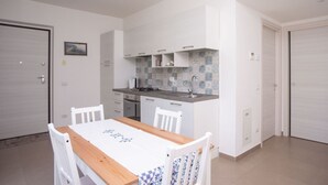 A compact kitchen with white cabinets, a wooden dining table, and a tiled backsplash. - S160 - Sirolo, brand new two-room apartment with terrace (Sirolo)
