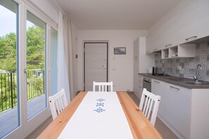 A dining area with a table, chairs, a kitchen with a sink, and a door leading to a balcony.