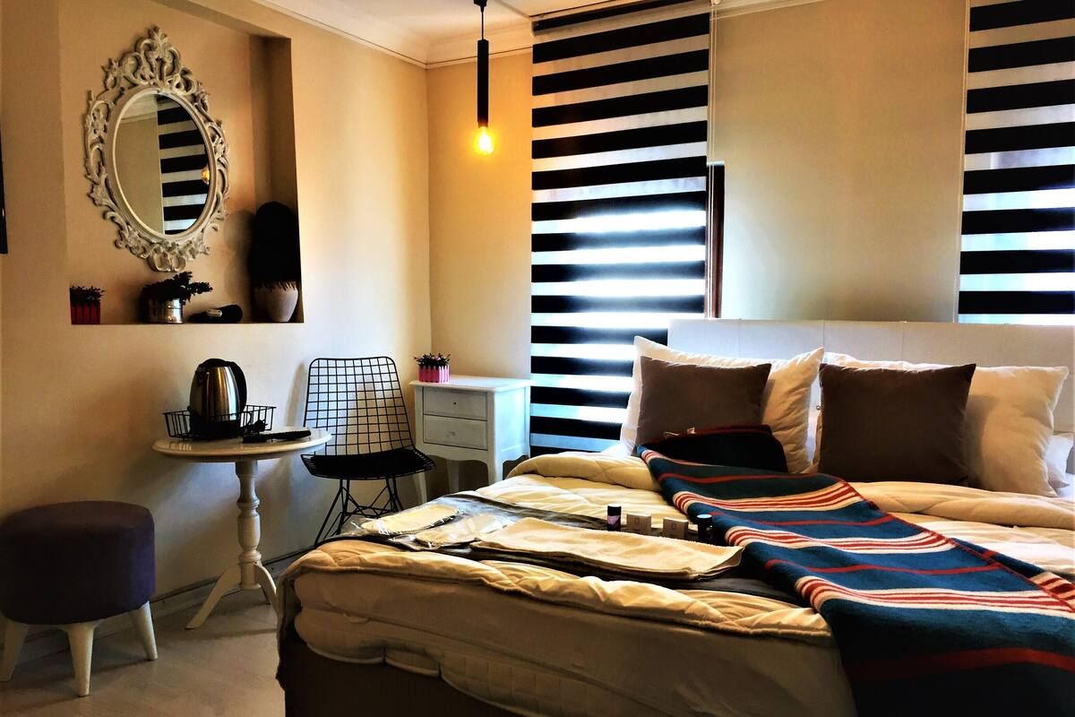 A bedroom with a bed, bedside table, chair, and a mirror on the wall.