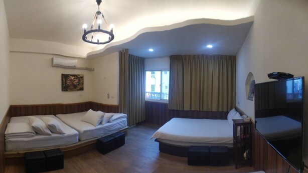Quarto de hotel com cama, sofá-cama, televisão e ar condicionado.