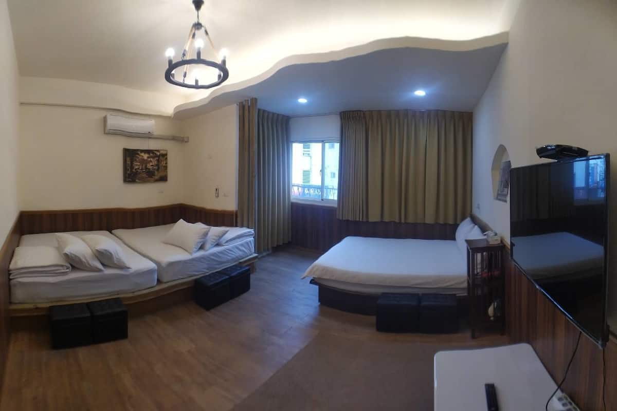 Una habitación de hotel con cama, sofá cama, televisión y aire acondicionado.