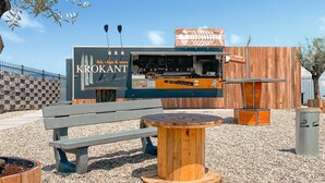 An outdoor food kiosk named Krokant with a wooden exterior, a bench, and a round table in the foreground.