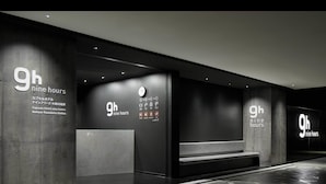 Entrada moderna de hotel con la señalización '9h nine hours', un reloj y un mostrador de recepción.