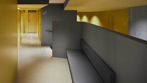 Un pasillo moderno con un banco, flechas direccionales en el suelo y una puerta al final.