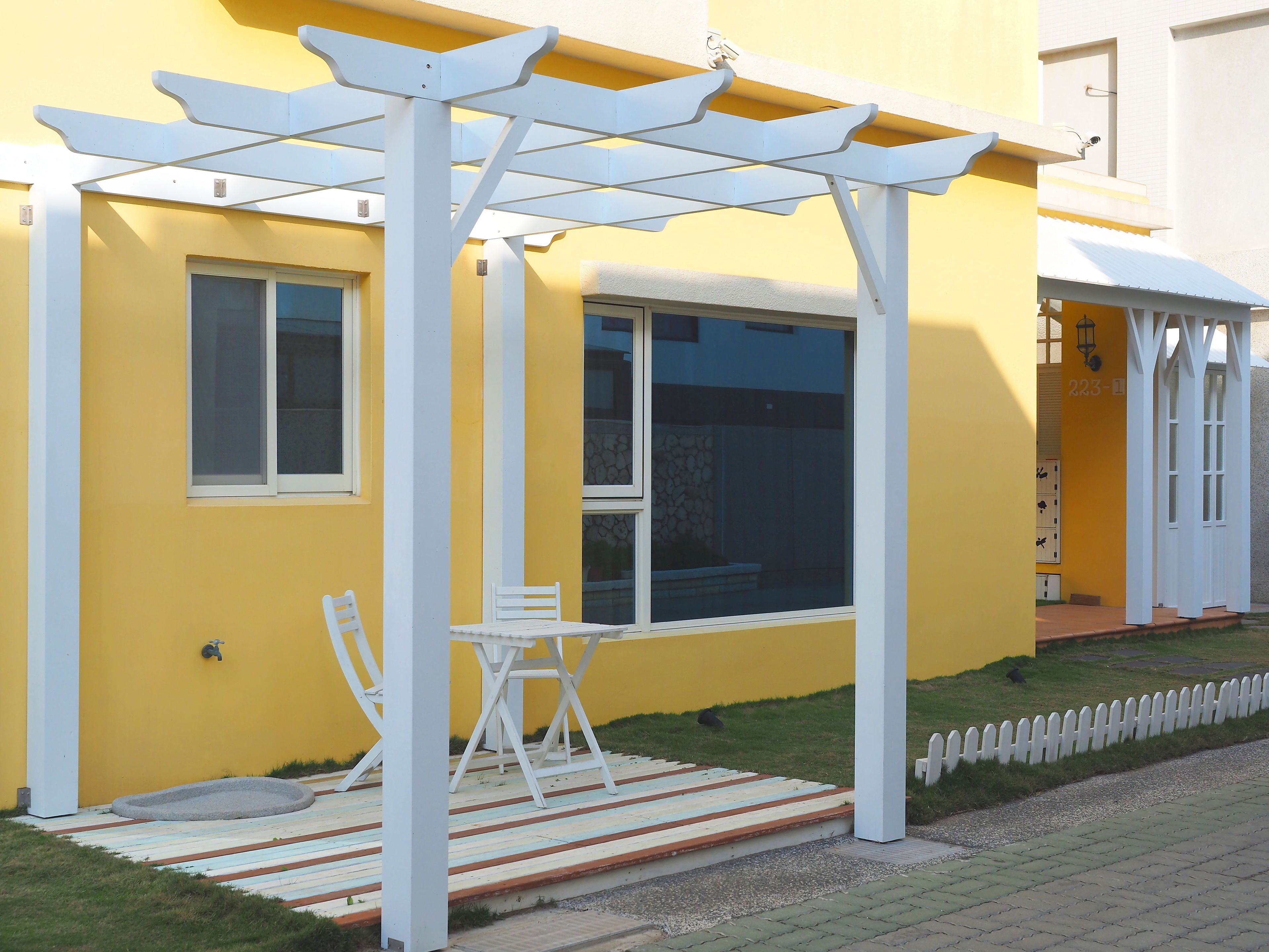 A yellow building with a white porch, a window, and a door.
