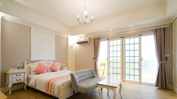 A bedroom with a bed, bedside table, chair, and a view of the outside through large sliding glass doors. - Good Time (Magong)