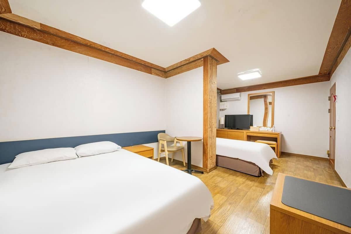 Une chambre d’hôtel avec deux lits, un bureau, une chaise et un téléviseur.