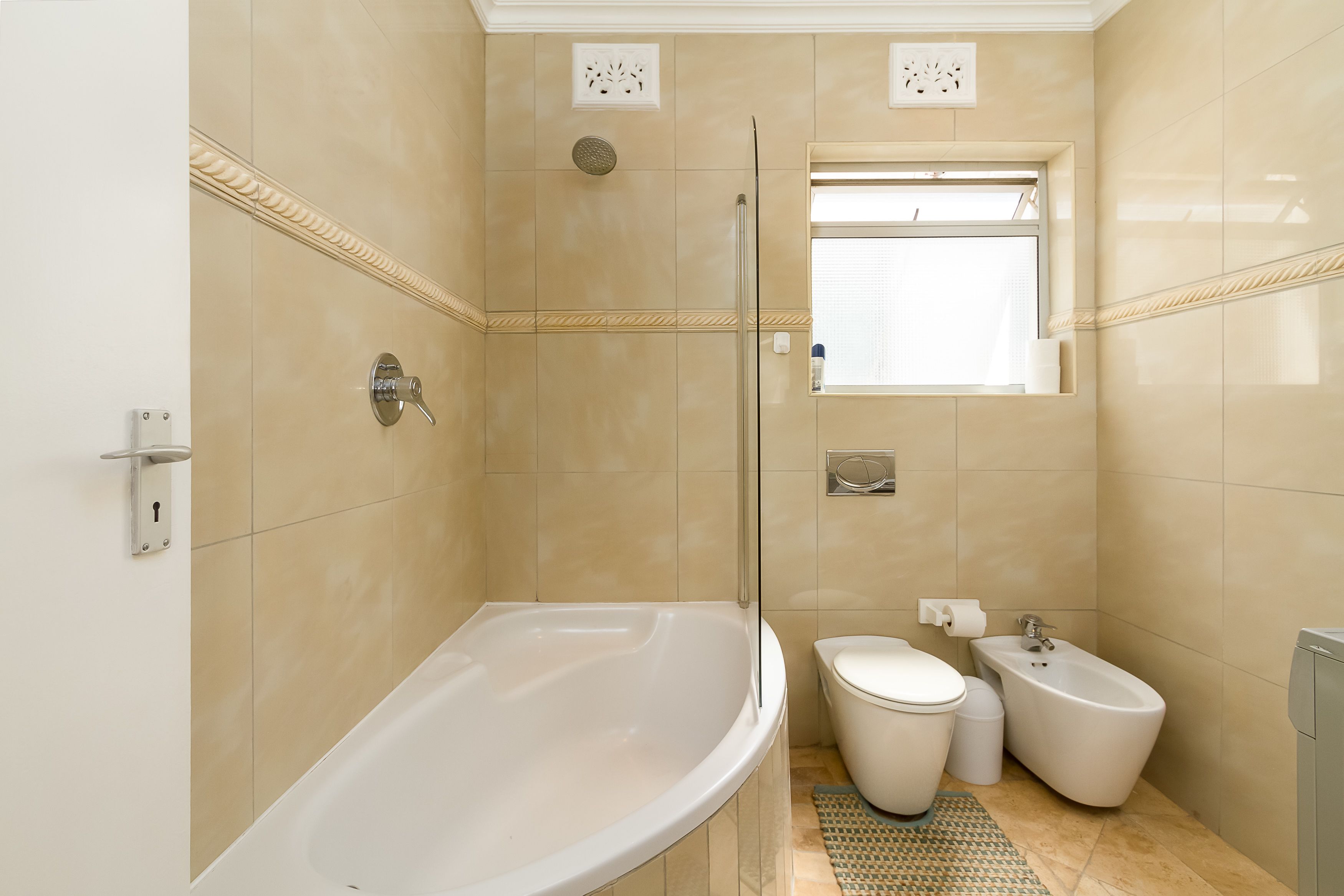 A modern bathroom with a bathtub, toilet, bidet, and a shower area.