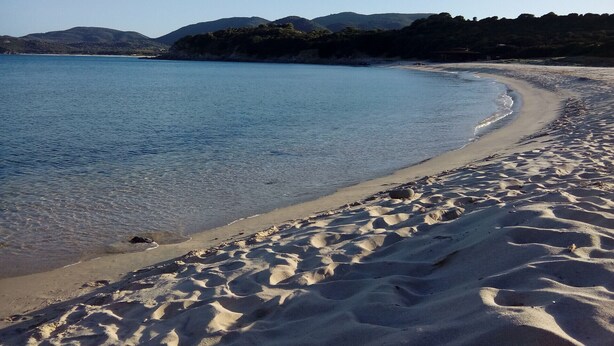 A sandy beach with clear blue water and distant mountains. - Villa Cinzia sea view (Porto Tramatzu)