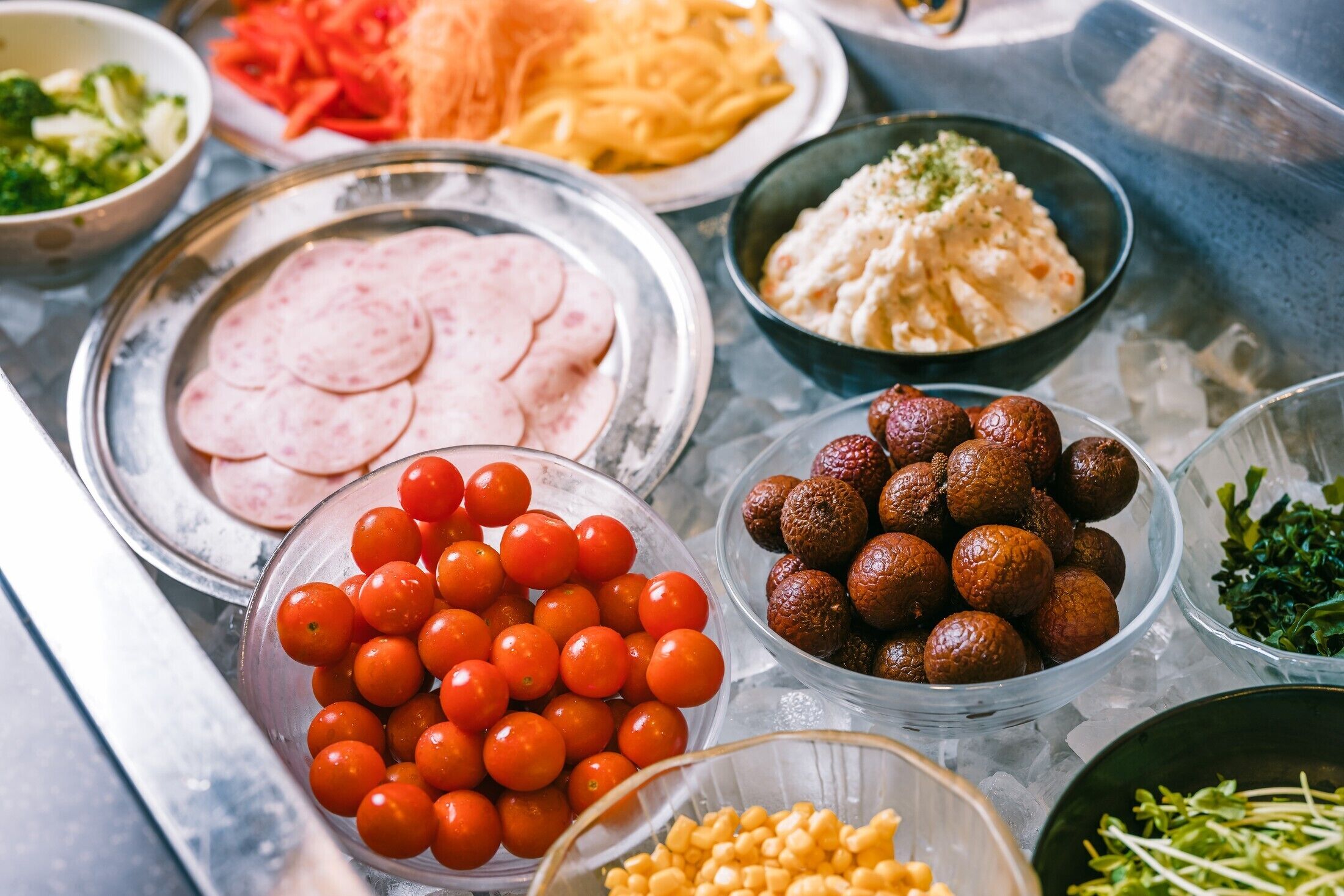 A buffet table with various food items including sliced meat, cherry tomatoes, and other dishes.