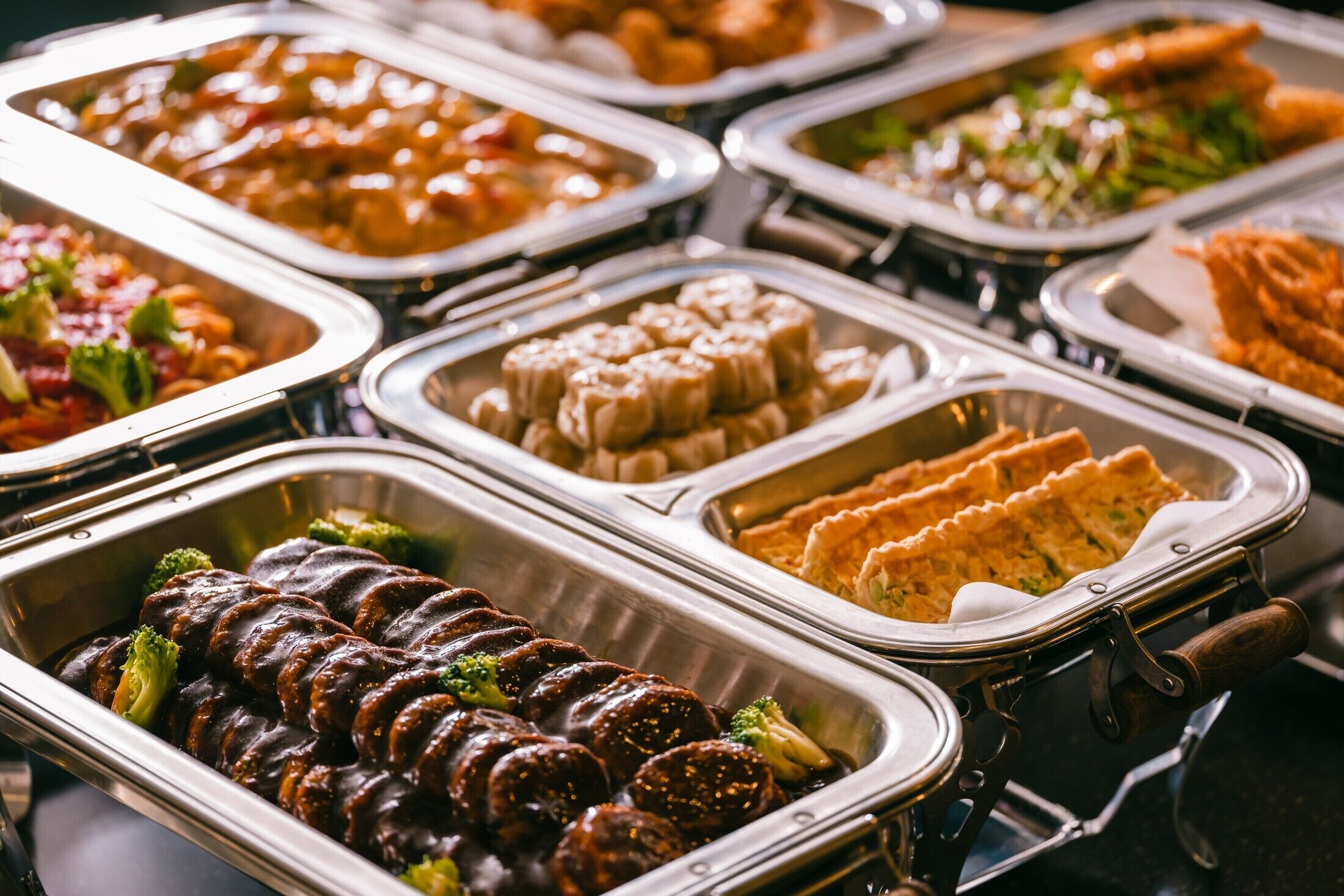 A buffet with various food options including meats, vegetables, and desserts.