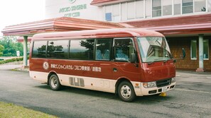 A red and white bus parked in front of a building with a sign that reads 'Micro Sunshine Golf Club.'