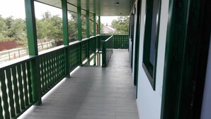 Un passadís cobert amb baranes verdes i un paviment de rajoles, que condueix a una escala.