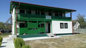 Edifici de dues plantes amb façana verd i blanca, un balcó al pis superior i un rètol que diu "CASA RENEA".