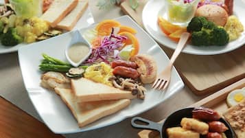 Un bufé de desayuno con diversos platos, como tostadas, huevos, salchichas y verduras.