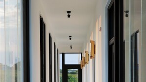 A modern hallway with large windows on both sides, leading to an open space. - Easy Inn (Hengchun)