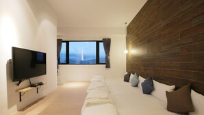A modern hotel room with a large bed, a flat-screen TV mounted on the wall, and a wooden accent wall. - Easy Inn (Hengchun)