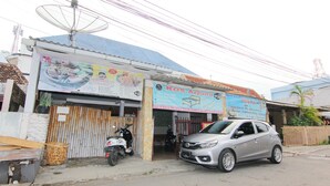 Un edificio con una antena parabólica, un letrero y un coche estacionado.