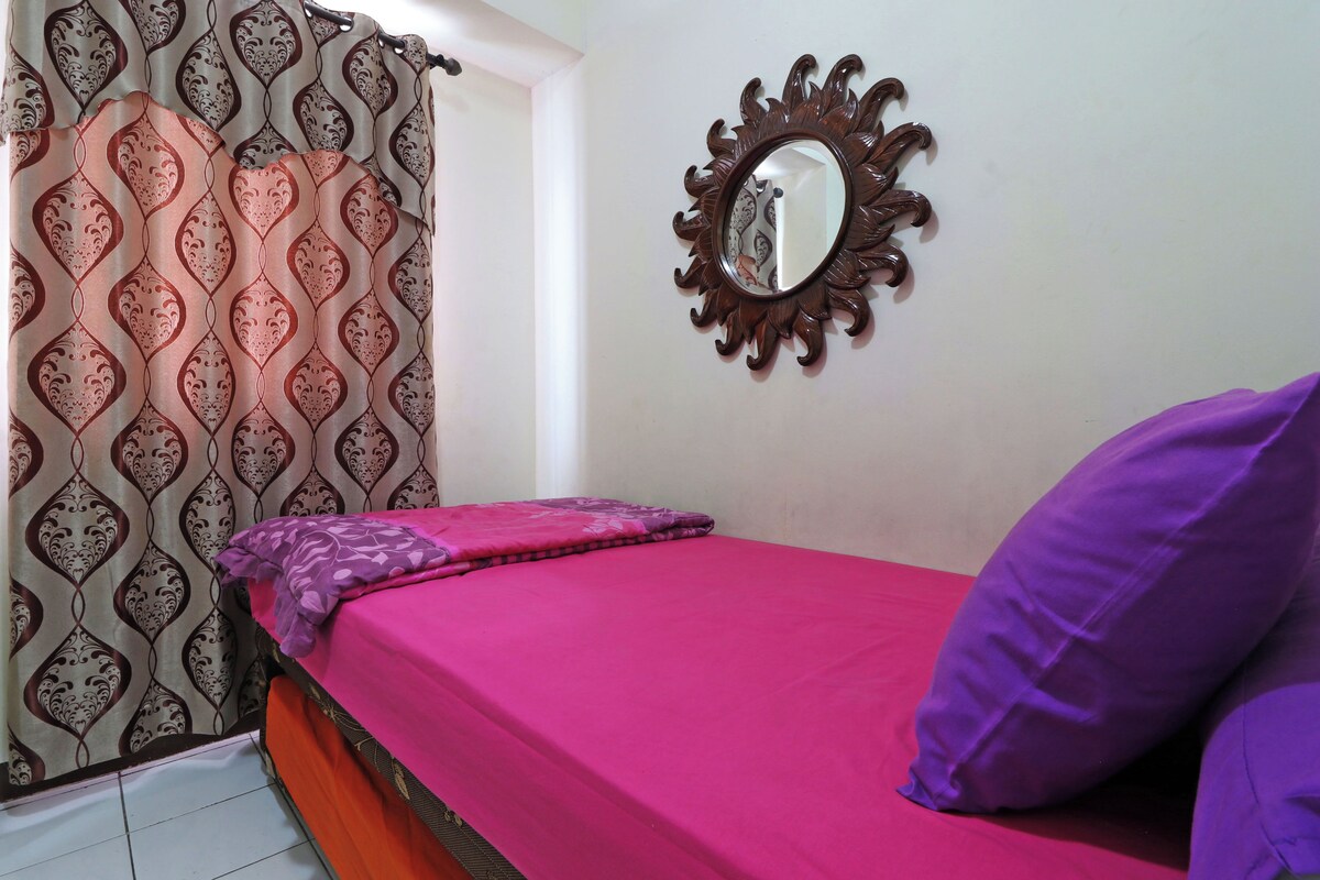 A bedroom with a bed, a mirror, and patterned curtains.