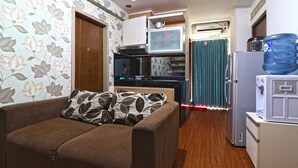 A compact living space with a sofa, kitchenette, and a water dispenser. - Inkubus Gateway Apartment Ahmad Yani by Ridwan (Bandung)