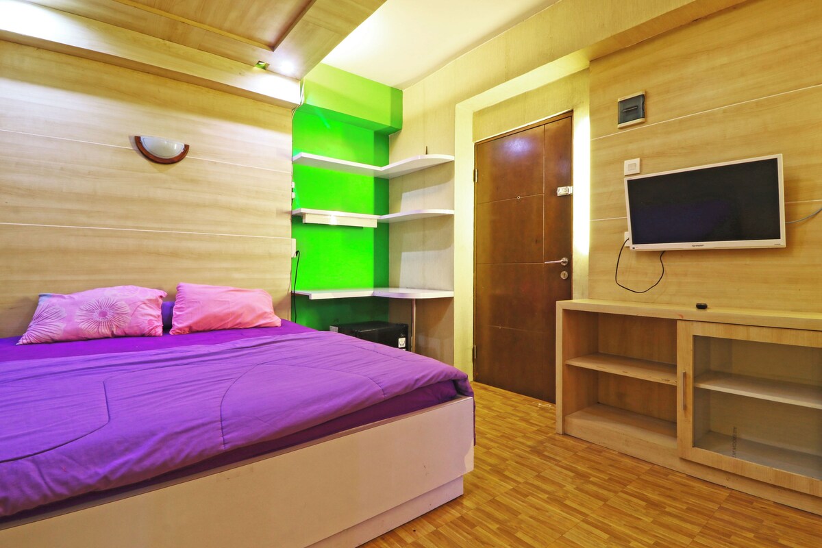 A bedroom with a bed, a TV, and built-in shelves.